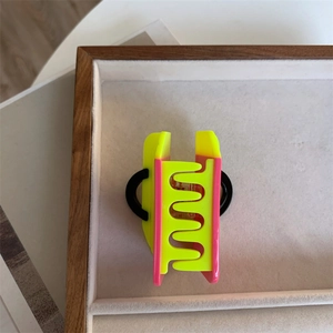 Detail shot of handbag-shaped acetate hair claw in neon yellow and bright pink