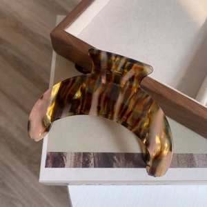 Detailed close-up of large acetate crescent hair claw with brown and pink tortoiseshell pattern