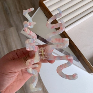 Detail shot of large pink marble acetate shark hair claw with wavy curve design