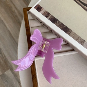 Elegant purple acetate bow hair claw clip made of translucent resin on jewelry tray