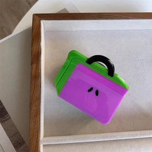 Detailed close-up of a green and purple bag-shaped acetate hair claw clip on a tray
