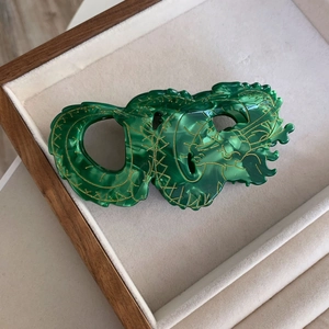 Detailopname van de smaragdgroene marmeren drakenhaarklem in een houten presentatiemand
