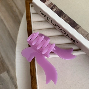 Detail view of the purple bow hair claw clip on a beige velvet display tray