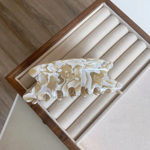 Détail de la pince à cheveux en acétate élégante avec texture marbrée crème et marron