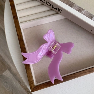Detail view of purple acetate bow hair claw clip on velvet tray with elegant golden spring