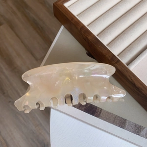 Détail d'une pince à cheveux élégante en acétate crème avec finition perle irisée