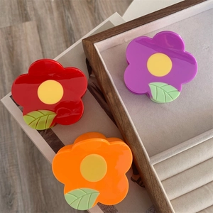 Detailed view of colorful flower-shaped hair claws in a wooden velvet jewelry box