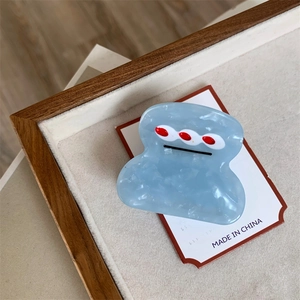 Detailed view of light blue marble acetate hair claw with minimalist cute face pattern