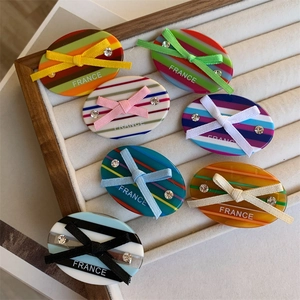 Colorful striped acetate hair clips with silk bows and crystals in a display tray