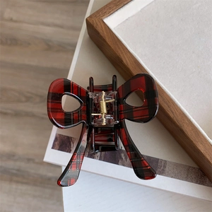 Macro shot of red plaid bow hair claw clip showing durable gold metal spring detail