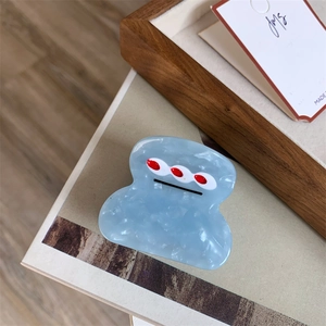 Close-up of light blue marble acetate hair claw clip with cute artistic face design