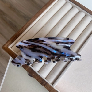 Détail d'une pince à cheveux en acétate marbré aux reflets bleus sur plateau de velours