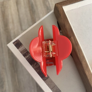 Close-up of a glossy red floral hair claw clip featuring a sturdy gold metal spring