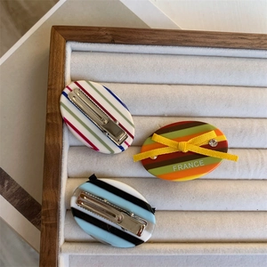Three striped acetate hair clips with bow in a white velvet jewelry tray, high quality finish