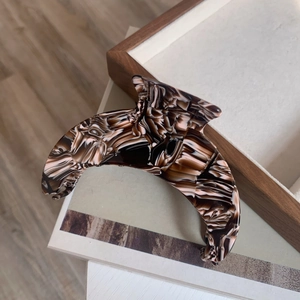 Detail of large crescent acetate hair claw clip with vintage brown marble pattern texture