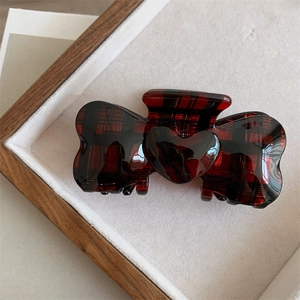 Detail view of red plaid acetate hair claw clip with heart ornament in wooden box