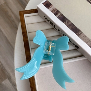 Detail of light blue bow hair claw clip with golden spring on a jewelry tray