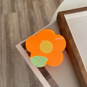 Medium orange flower hair claw clip with green leaf detail for women's hairstyles