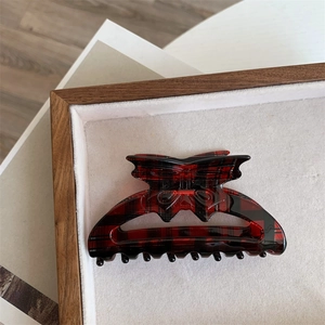 Macro detail of red and black plaid bow hair claw clip in a wooden display tray
