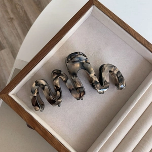 Close-up of marble pattern acetate hair claw with curved wave design on wooden tray