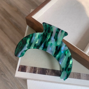 Macro detail of large acetate claw clip with dark green and blue marble texture
