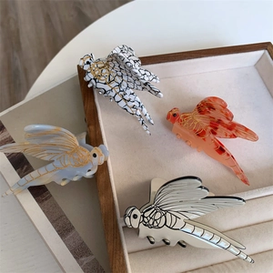 Detailed overhead view of acetate dragonfly hair claws in four elegant marble patterns