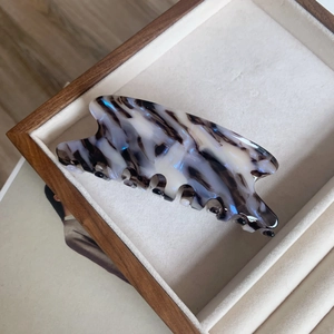 Détail d'une grande pince à cheveux en acétate marbré dans un coffret à bijoux de luxe