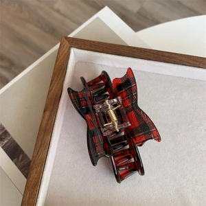 Close-up of red tartan butterfly hair claw clip with golden metal spring detail