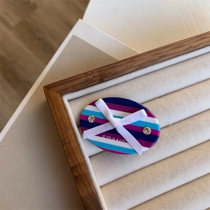 Macro shot of acetic acid hair clip with colorful stripes, white bow and rhinestones