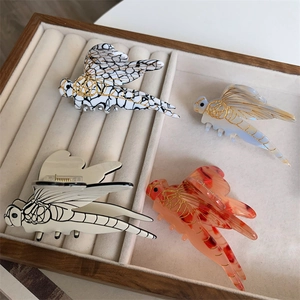 Chic dragonfly hair claws in marble and tortoiseshell patterns on a velvet display tray