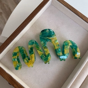 Detailed macro view of an oversized acetate hair claw with green and yellow marble patterns