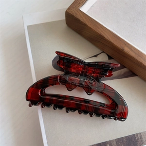Detail of red plaid butterfly hair claw clip with star accent and textured finish