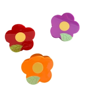 Three colorful flower-shaped hair claws in red, purple, and orange on white background