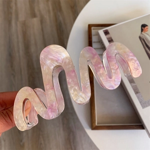 Détail de la texture marbrée de la grande pince à cheveux ondulée en rose et crème