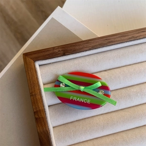 Macro shot of striped acetate hair clip with green silk bow and rhinestone details