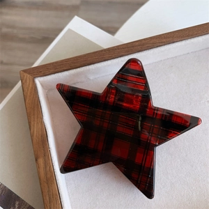 Detailed close-up of a star-shaped hair claw clip with a red and black plaid pattern