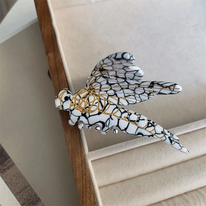 Detailed view of dragonfly hair claw featuring white marble texture and gold metal accents