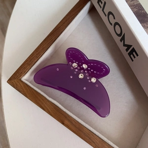 Détail d'une pince à cheveux papillon en acide acétique violet avec des strass brillants