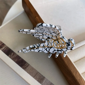 Detailed view of dragonfly hair claw featuring black marble texture and gold wing veins