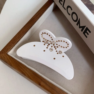Vue détaillée d'une pince à cheveux papillon blanche ornée de strass brillants décoratifs