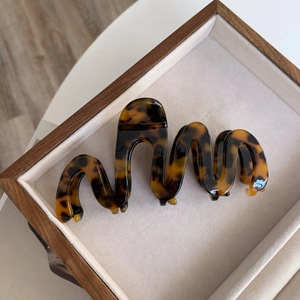 Close-up of oversized tortoiseshell acetate hair claw with wavy design in a display tray