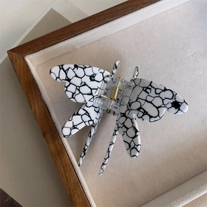Close-up of animal-themed dragonfly hair claw with marble texture and golden spring mechanism