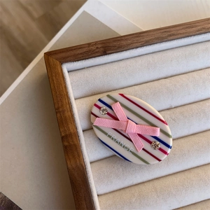 Macro detail of acetate hair clip with colorful stripes, pink bow and rhinestone inlay