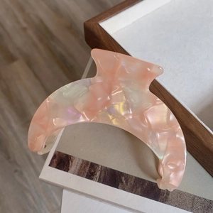 Macro detail of crescent acetate hair claw clip with pink marble pearl texture