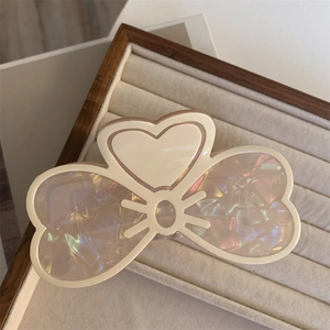 Dettaglio di un fermaglio per capelli a cuore bianco crema con finitura perlata iridescente