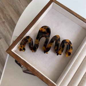 Detailed view of oversized acetate hair claw clip with tortoise pattern on a jewelry tray