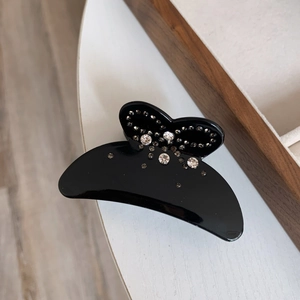 Détail d'une pince à cheveux noire en acétate ornée de strass brillants et élégants