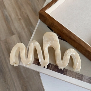Detailed view of oversized ivory cream acetate hair claw clip with wavy marble texture