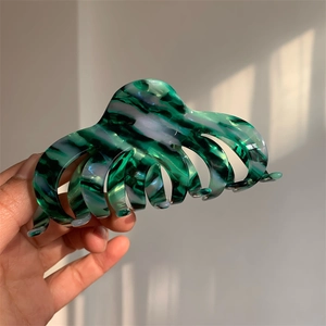 Macro detail of large acetate hair claw clip featuring green marbled oil painting texture