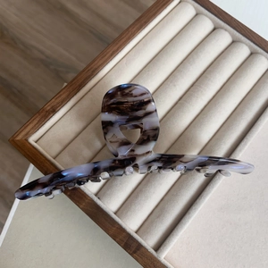 Detail view of the polished marble pattern acetate hair claw clip on velvet display